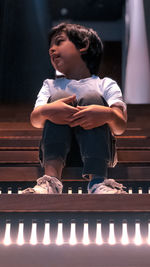 Low angle view of boy sitting on staircase