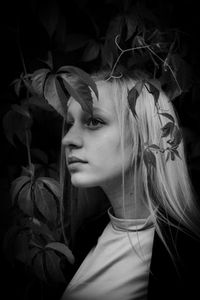 Young woman looking away by plants