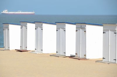 Huts at beach against sky on sunny day