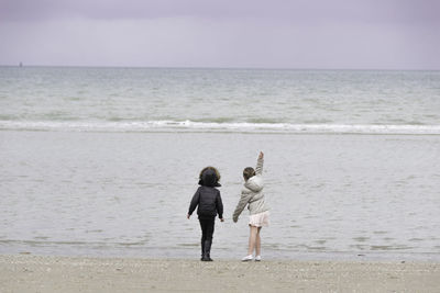 Rear view of girls standing at beach