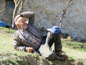 Full length of man sitting by wall