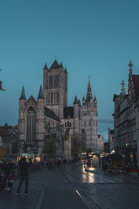 Group of people on street amidst buildings at dusk