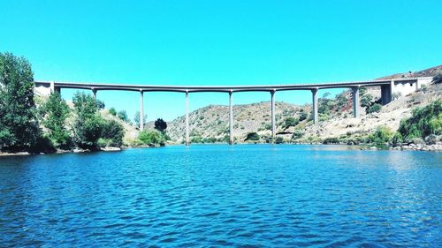 Bridge over sea against clear blue sky