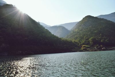 Scenic view of river by mountains against clear sky