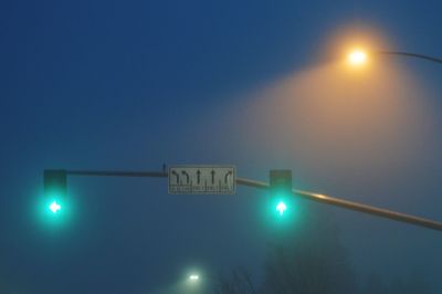 Low angle view of illuminated street light against blue sky