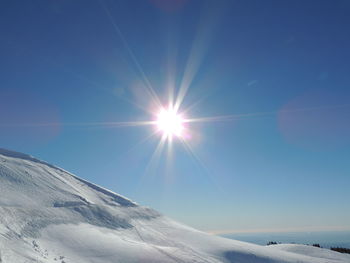 Scenic view of snowcapped mountains against sky on sunny day