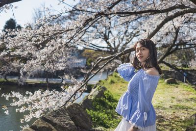 Full length of woman standing by flower tree