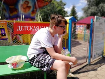 Sad boy looking away while sitting in amusement park