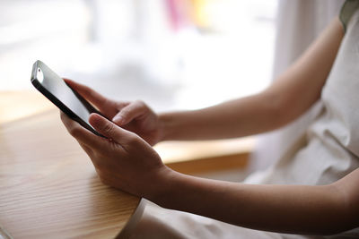 Midsection of woman using mobile phone on table