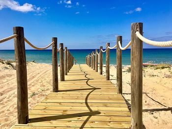 Wooden posts on beach against sky