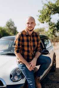 Portrait of young man sitting on car