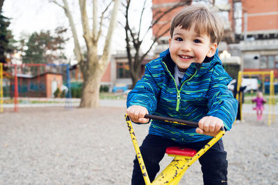 Portrait of smiling boy playing on seesaw at playground