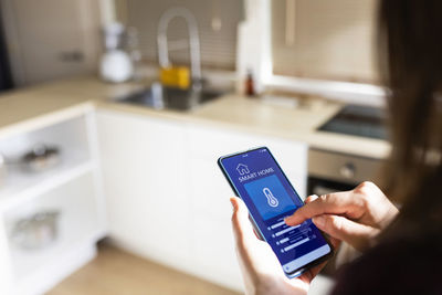 Woman using smart home application on phone at home