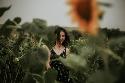 Young woman standing amidst sunflowers on field