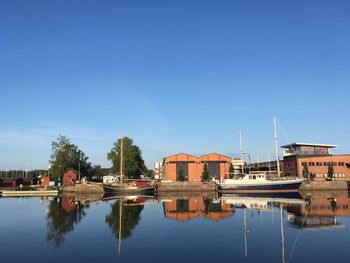 Reflection of building in lake against clear blue sky