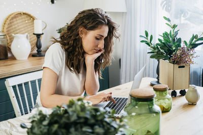 Beautiful woman in the kitchen working on a laptop.