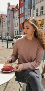 Young woman sitting on table against buildings in city