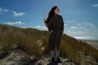 Woman standing on beach against sky