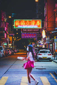 Full length of woman walking on illuminated city street