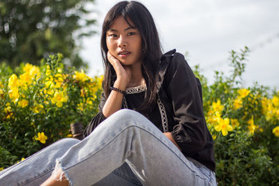 Portrait of young woman against flowering plants