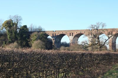 Arch bridge on field against clear sky