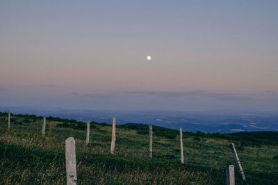 Fence on field against sky at dusk