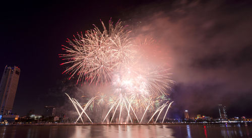 Firework display over river against sky at night