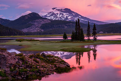 Scenic view of lake by mountains against sky during sunset