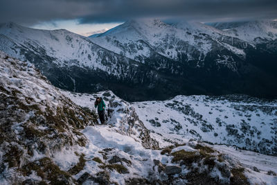 Woman hiking on snowcapped mountain during storm cloud