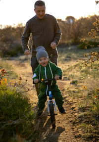 Rear view of man riding bicycle on field