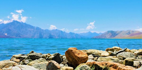 Scenic view of sea and mountains against blue sky