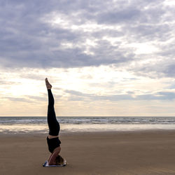 Young woman practicing yoga on the beach in newborough, north wales, uk