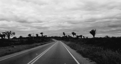 Road by trees against sky