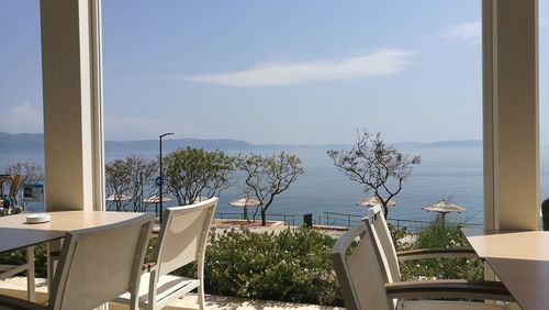 Chairs and table by swimming pool against sky