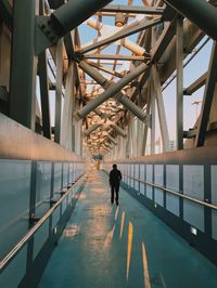 Rear view of a man walking on pedestrian  bridge 