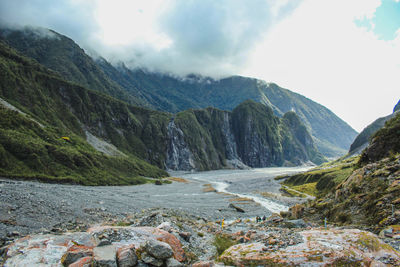 Scenic view of river flowing amidst mountains against sky