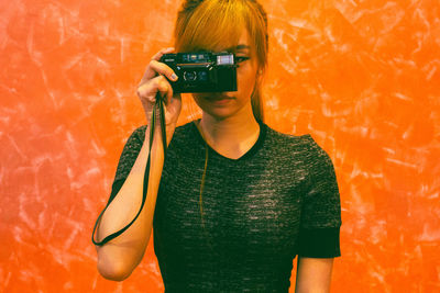 Man photographing orange camera