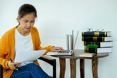 Young woman using phone while sitting on table