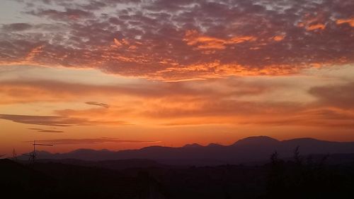 Silhouette mountains against dramatic sky during sunset