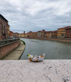 Buildings by river against sky