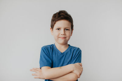 A preschool boy in a blue t-shirt on a light background shows a thumbs up. high quality photo