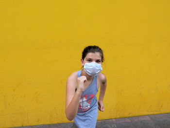 Portrait of boy standing against yellow wall