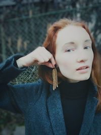 Close-up portrait of young woman holding buds as earrings