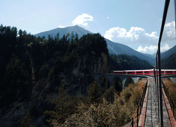 Scenic view of mountains with a train on a bridge
