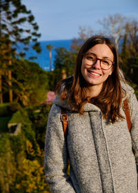 Portrait of young woman standing against trees