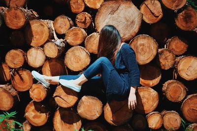 Side view of woman sitting on wooden log