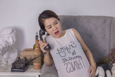 Pregnant woman talking on rotary phone while sitting at home
