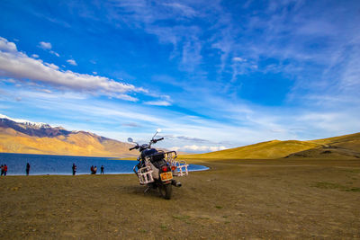 People cycling on land against sky
