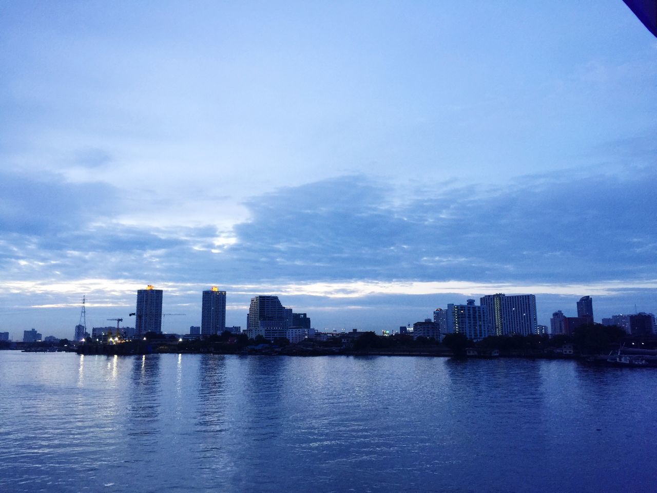 architecture, building exterior, built structure, city, water, waterfront, sky, cityscape, skyscraper, river, reflection, urban skyline, cloud - sky, modern, skyline, office building, blue, sea, tall - high, cloud