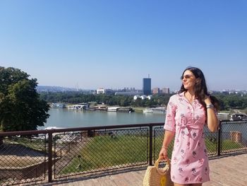 Woman standing by railing against clear sky